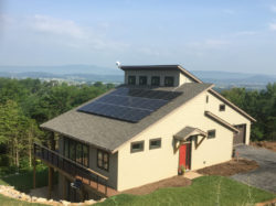 A house outfitted with solar panels and large windows on one side.