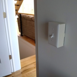 A photo of a light switch where the cover is extended a couple of inches away from the rest of thewall.