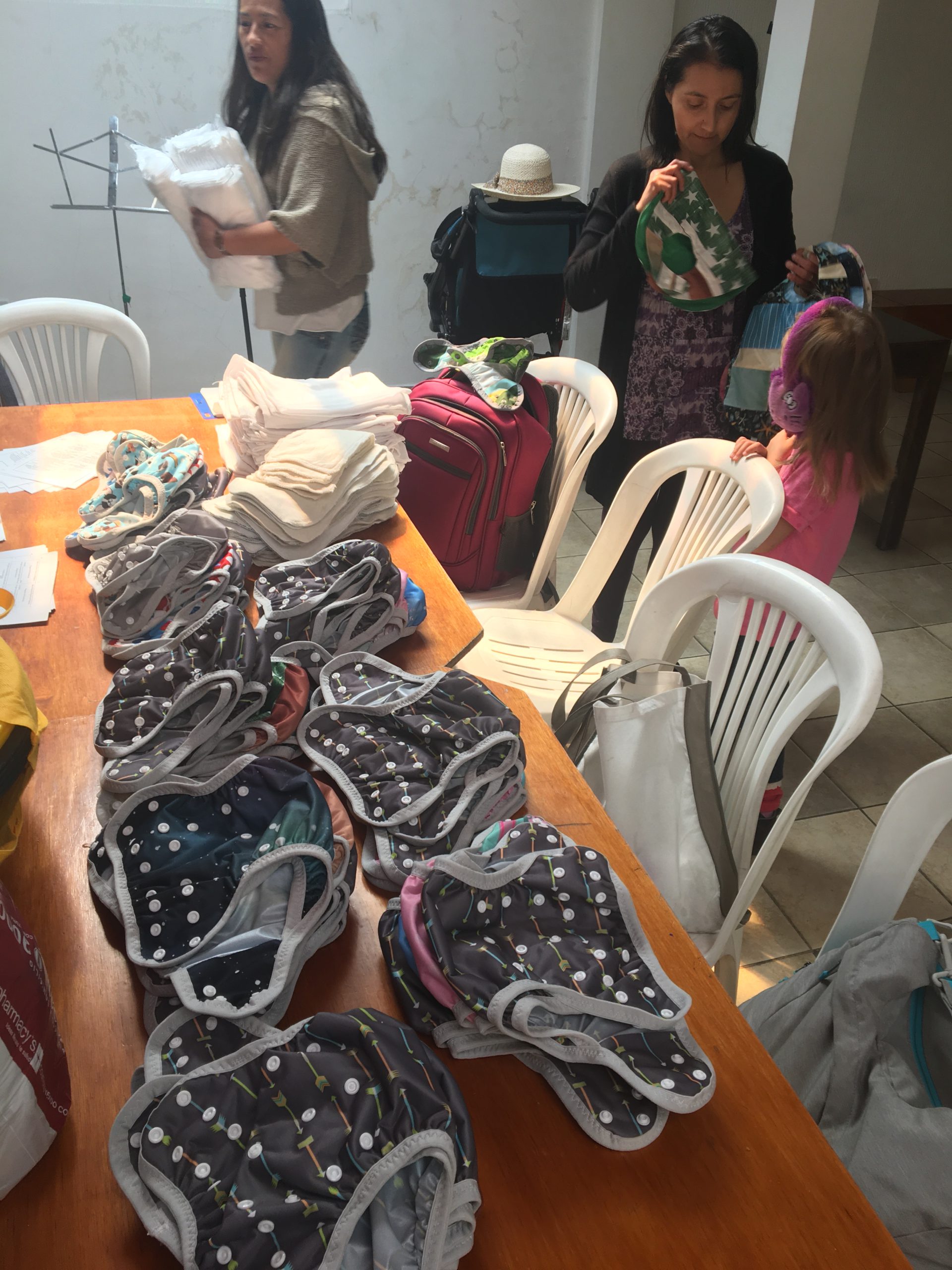 Delicia Brava, with her daughter on the right, sews reusable cloth diapers for refugee mothers. Alba Silva, left, helps distribute the diapers through the Refugee Project at Quito Mennonite Church. Photo provided by Peter Wigginton.