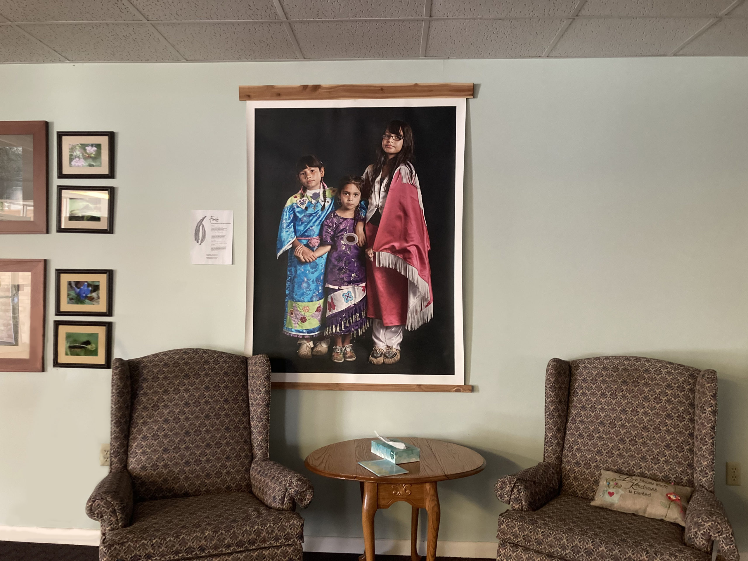 A photograph by Potawatomi artist Sharon Hoogstraten hangs in the foyer at Waterford Mennonite Church. The portrait features three Potawatomi dancers, Selphie, age 8, Lilly, age 6, and Mimike, age 10. Sharon, from Kalamazoo, Michigan, said in a statement for the Citizen Potawatomi Nation Cultural Heritage Center: “Preserving the faces, stories, and regalia of modern Potawatomi will contribute to a better understanding of their transformed place in the diverse life of America.” Photo by Sierra Ross Richer.
